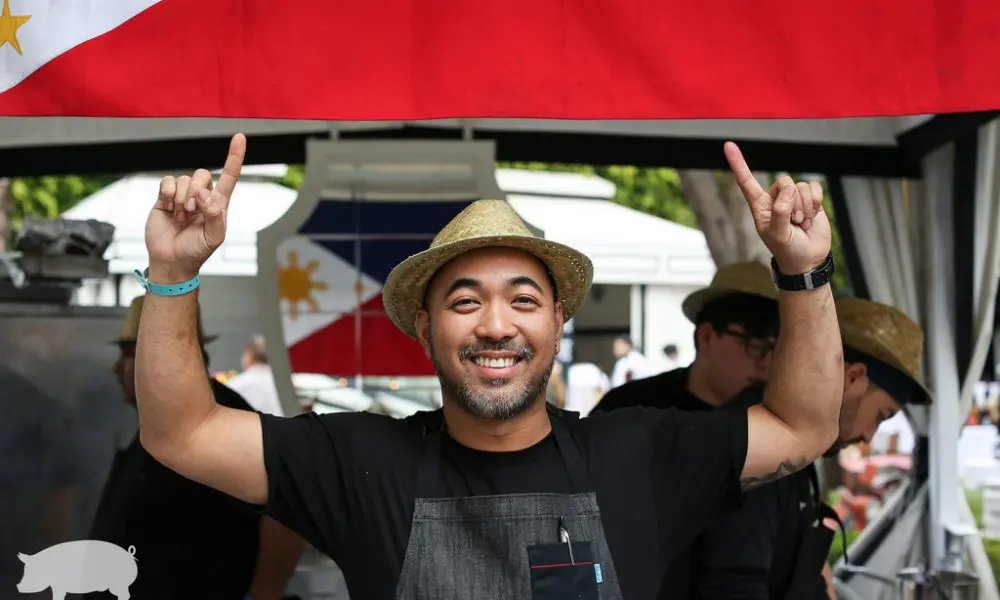 personal_photo-740-1000x600 A man in an apron and hat is holding up two fingers.